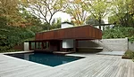 A board-formed-concrete retaining wall and stair lead to the pool house.