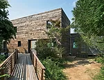 Located in a remote town of fewer than 1,000 residents on the North Fork of Long Island, the house is entered via a wood platform to the south.
