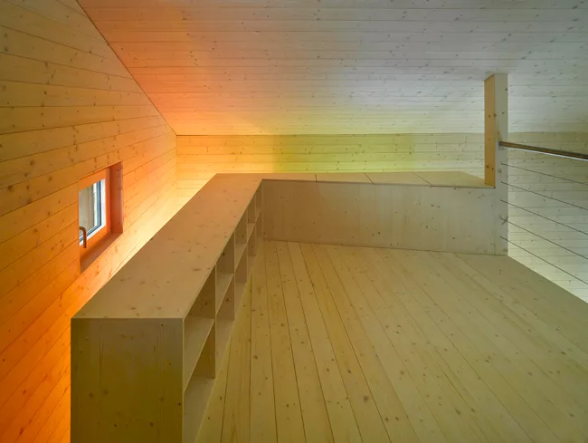 A stair leads to a mezzanine that doubles as a guest bedroom. For panache, the architect stained the fir cladding in acidic hues of green, orange, and yellow.