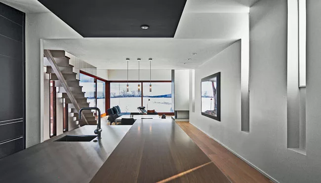 Inside, the kitchen, dining, and living spaces open out to an expansive view.