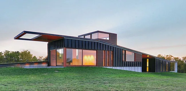Set into a gentle grassy slope, the house has a copper roof and concrete-fiber rainscreen walls with black aluminum fins