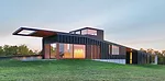 Set into a gentle grassy slope, the house has a copper roof and concrete-fiber rainscreen walls with black aluminum fins