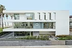 The minimalist three-story house is punctuated by movable walls on the top floor and deep overhangs.