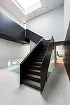 The sculptural stair that connects the two wings of the house is custom-fabricated from folded blackened-steel plate.