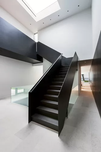 The sculptural stair that connects the two wings of the house is custom-fabricated from folded blackened-steel plate.
