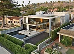An outdoor room with a lap pool, reflecting pool, and seating areas wraps the house on the ocean-facing side. The hedge-lined walkway softens the transition between the street and the entry and helps 