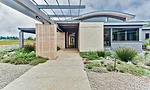 A steel pergola floats above a sandstone walkway.