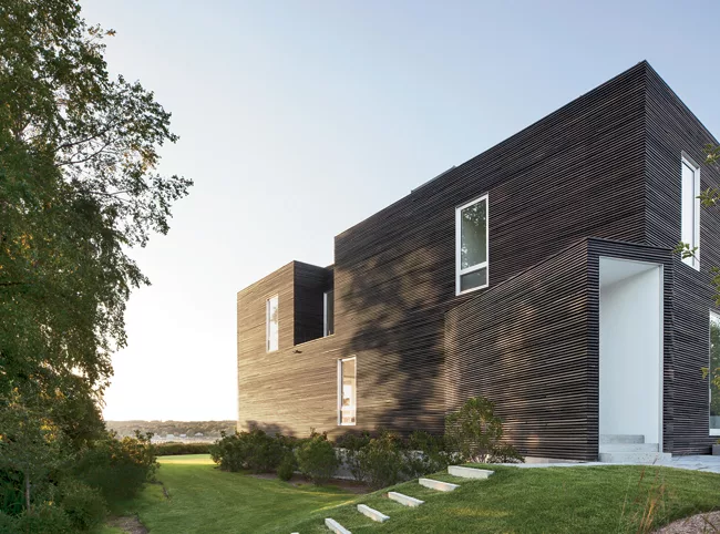 The dark exterior of the 2,200-square-foot house is clad in custom-milled slats of cypress. Each 1 1/2”-by-3” slat has been charred, brushed, and oiled.