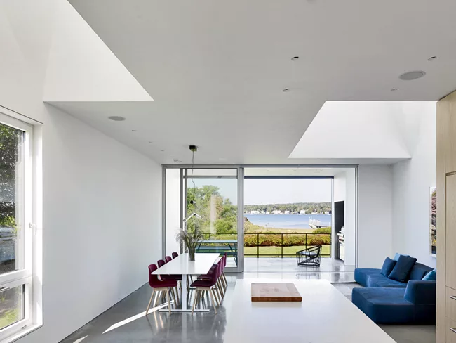 Large cutouts in the ceiling flood the ground-floor public space with natural light as it overlooks Quonochontaug Pond.