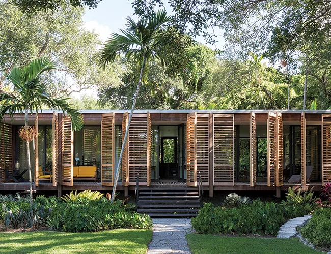 Red cedar folding shutters extend across the house's front facade.