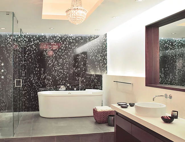The master bath's soaking tub and glass-enclosed shower are backed by a slab of Black Spring granite.