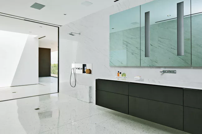 In the master-bathroom suite, his bath is one large shower room with drainage built into the terrazzo floor.