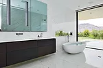 The marble-topped oak vanity spans 12 feet in length. Her bath features a freestanding egg-shaped tub with a rain shower just beside it. Glass pocket walls in both baths give way to outdoor terraces.