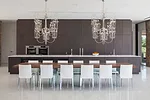 The dining table appears to float, thanks to its base of angled glass fins. The architects installed two chandeliers because “one is a focal point, but two create a line,” says Kelly.