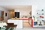 Glossy white kitchen cabinets serve as a neutral backdrop for the client’s collection of vintage furniture, such as the early 1970s-era dining table by Vladimir Kagan. 