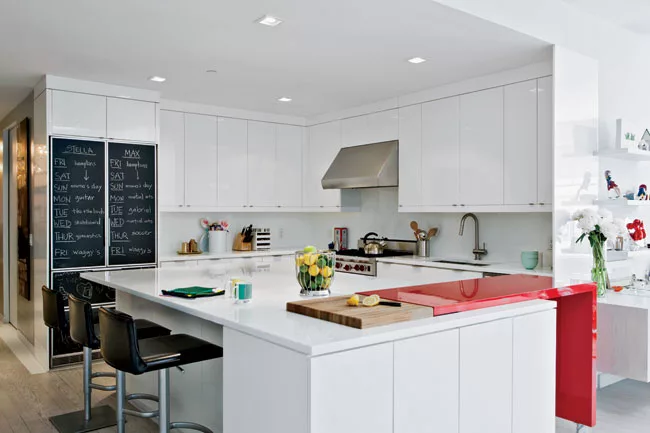 To introduce some color, Reddy created an ingenious modular bar—in a vibrant red—that glides in and out of the counter, extending the surface for serving and visually separating the kitche