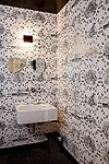 The powder room features traditional materials with a twist. The black-and-white wall covering is a slightly risqué variation on toile, the sink was originally designed for the German school syst