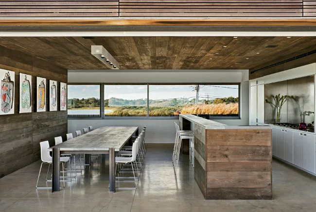 Oak dominates the kitchen, save for white lacquer cabinetry that conceals appliances and frames a stainless-steel backsplash.