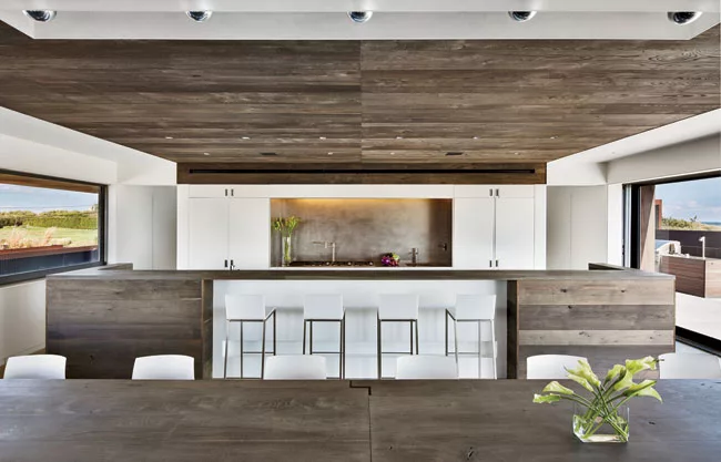 Oak dominates the kitchen, save for white lacquer cabinetry that conceals appliances and frames a stainless-steel backsplash.