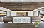 Oak dominates the kitchen, save for white lacquer cabinetry that conceals appliances and frames a stainless-steel backsplash.