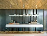  A black perforated-metal screen behind the kitchen's floating cooktop conceals downdraft vents.