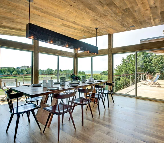 Located just to the right of the kitchen on the house's east side, the dining room opens to a series of decks and overlooks a backyard pond. The custom light fixture reintroduces the black perforated