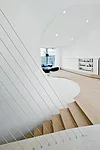 Dynamic washed oak stairs flow into the house's open public spaces detailed with limestone kitchen and dining room floors, clay-based stucco walls, and custom downlights in the sloping ceiling.