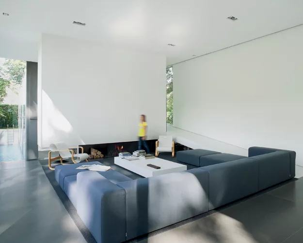 The concrete chimney wall of the living area is suspended over the hearth. A ramp on the northeast side of the house leads up to the second-level bedrooms for the son and daughter.