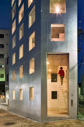 Reflecting light into the interior, silver paint coats the building’s exterior. Devoid of scale-defining sashes, the windows read as wall openings that widen as the building ascends. The double-