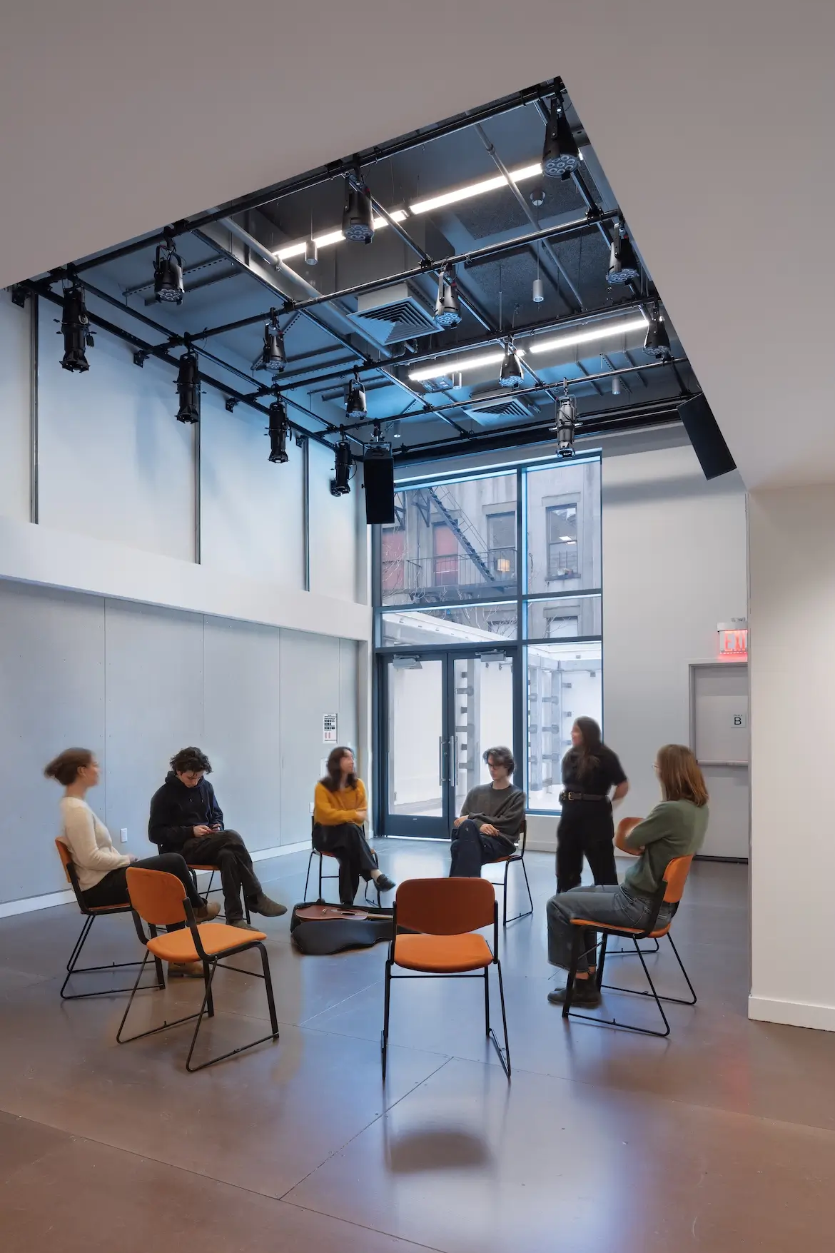 people gathering in chairs in a studio space.