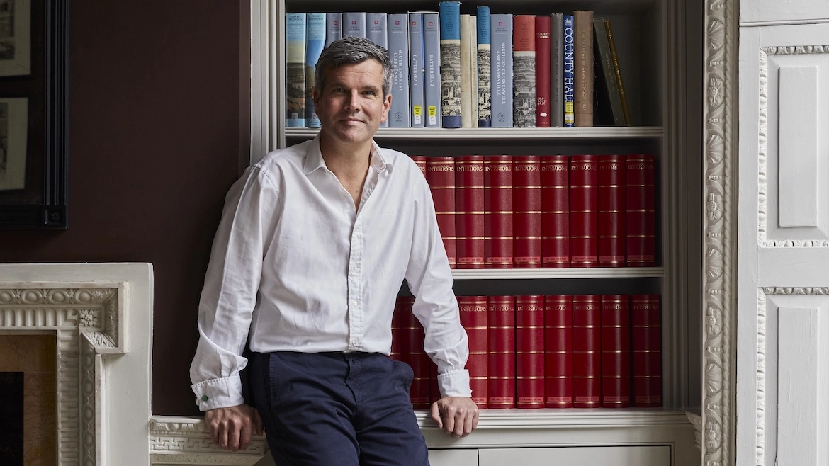 Portrait of English architect Ben Pentreath against a bookcase