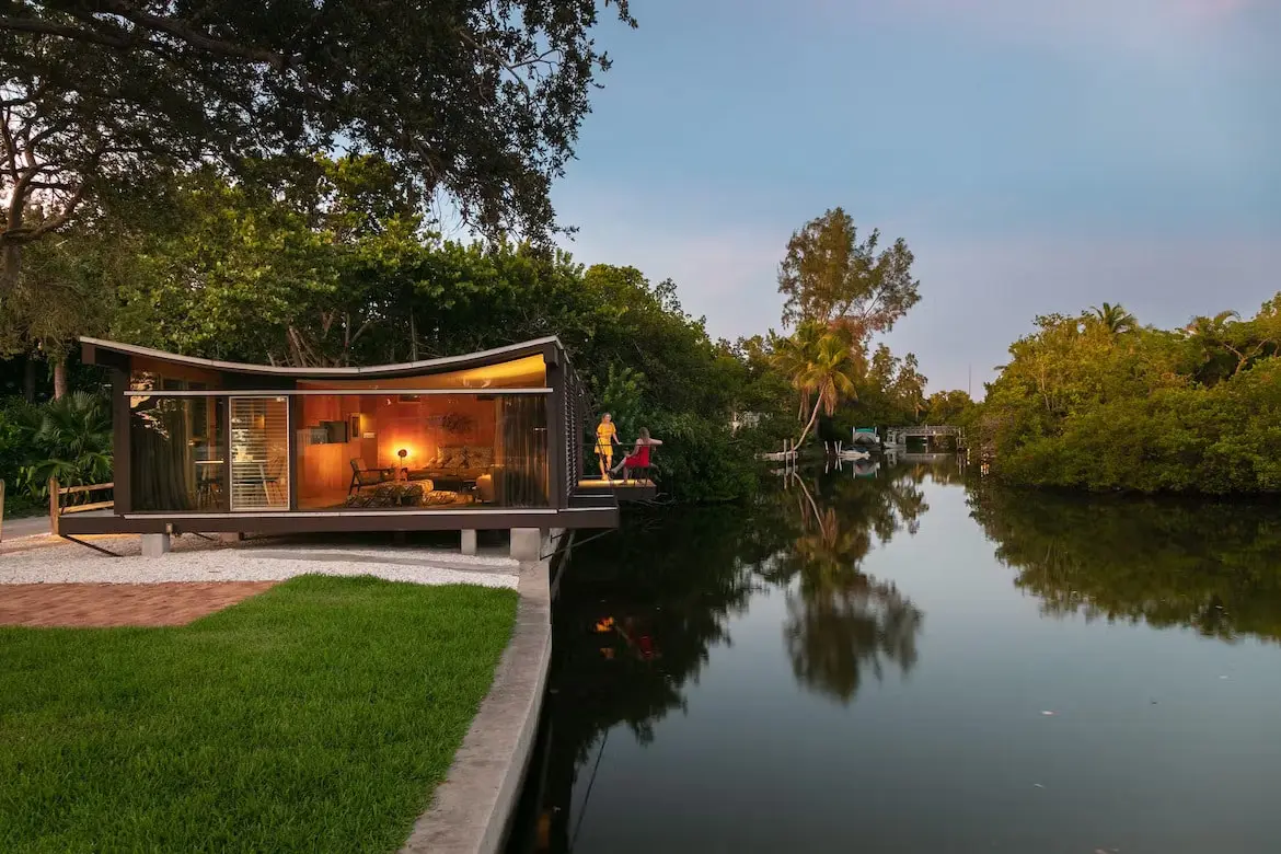 a modernist cottage extending over a canal in florida.