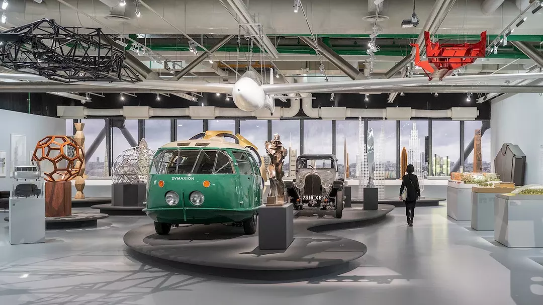 view of large scale-objects, including automobiles, on display in an exhibition
