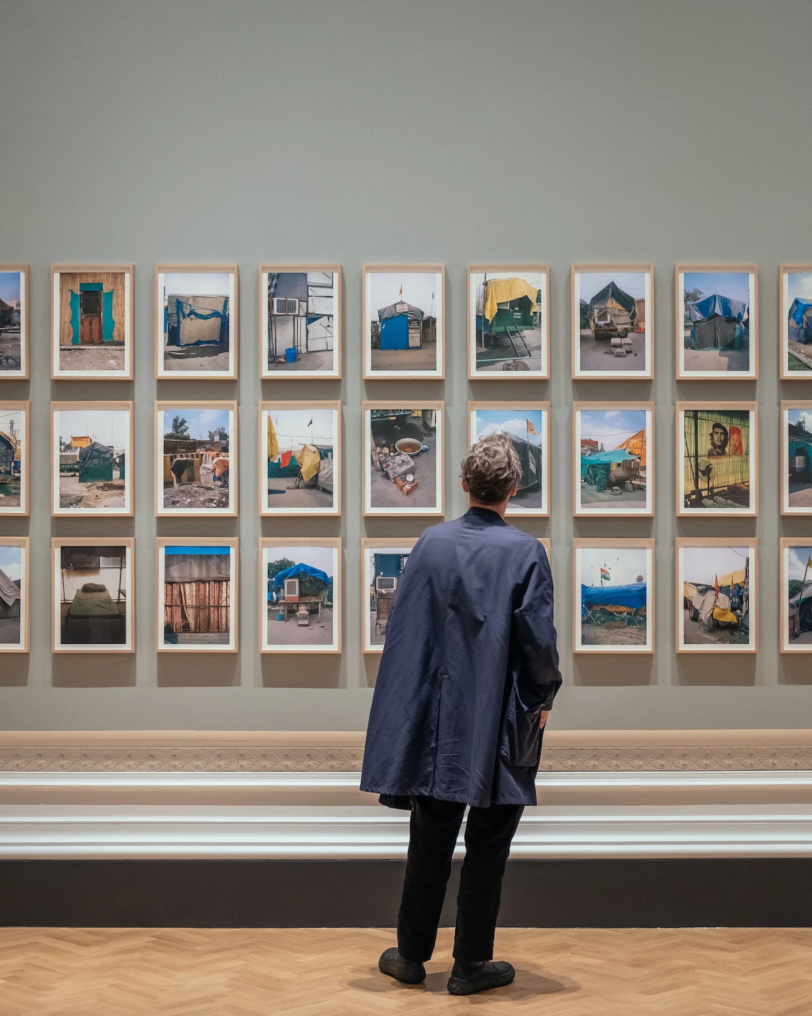 a museum-goer looks at photographs displayed on a gallery wall 