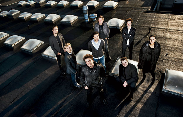 Bjarke Ingels (standing at center, bottom) surrounded by his seven partners in BIG.